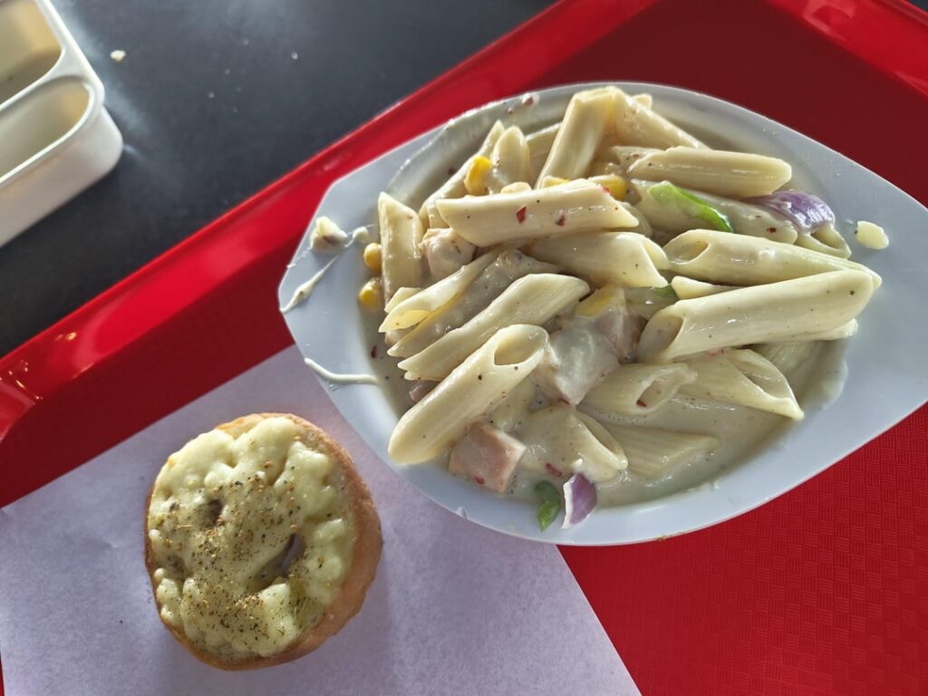 Chicken pasta in white sauce with small garlic bread