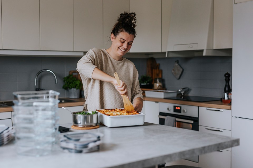 Woman portioning lasagna in her kitchen.