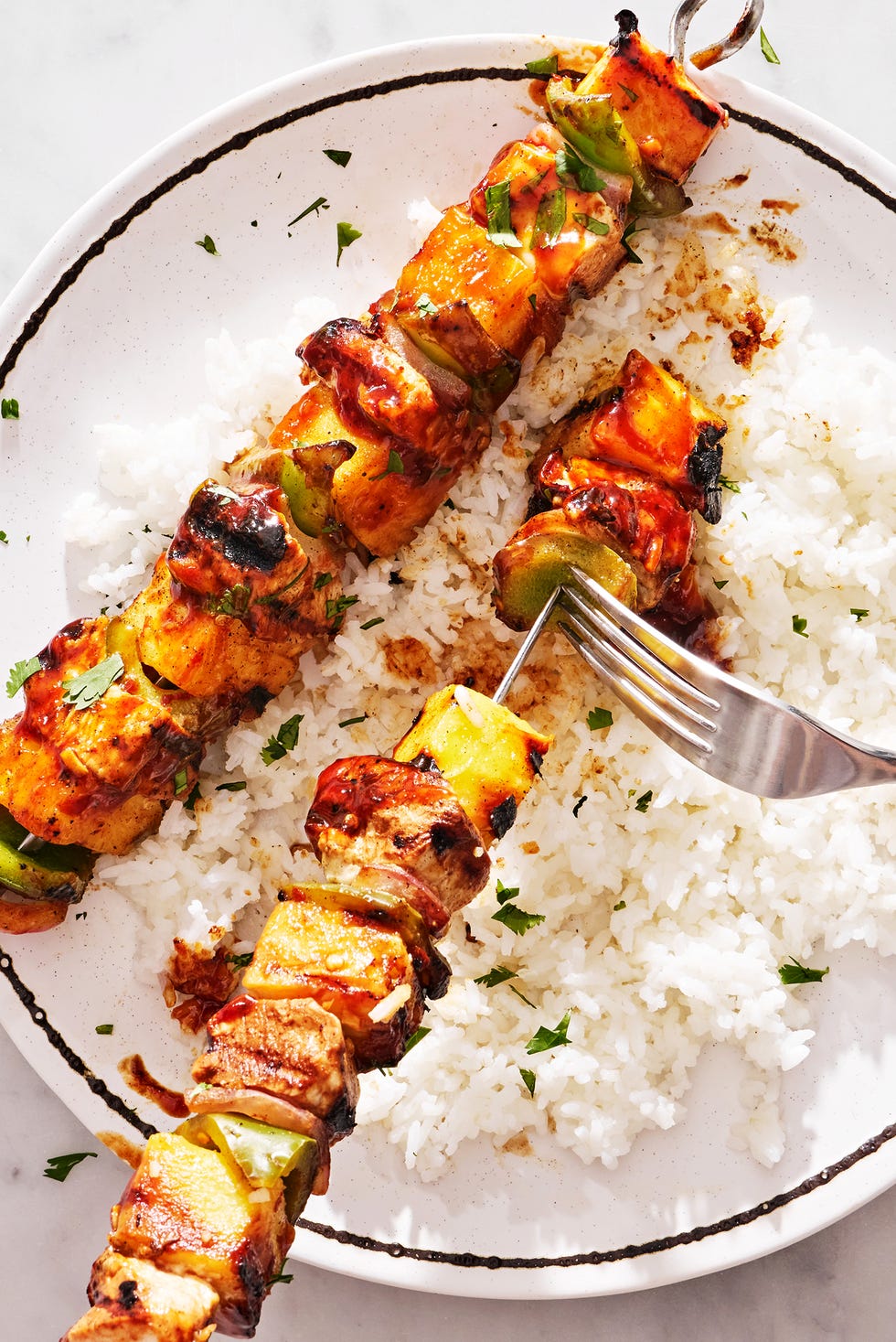 chicken, pineapple, and peppers on a skewer basted with teriyaki