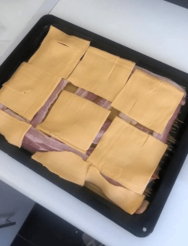 Bacon and cheese squares arranged on a baking sheet.