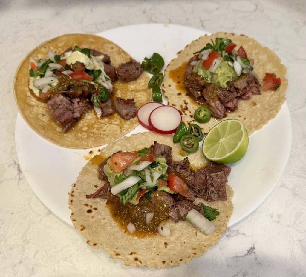 Carne Asada Tacos with roasted habanero salsa, avocado crema, guacamole, and pico de gallo