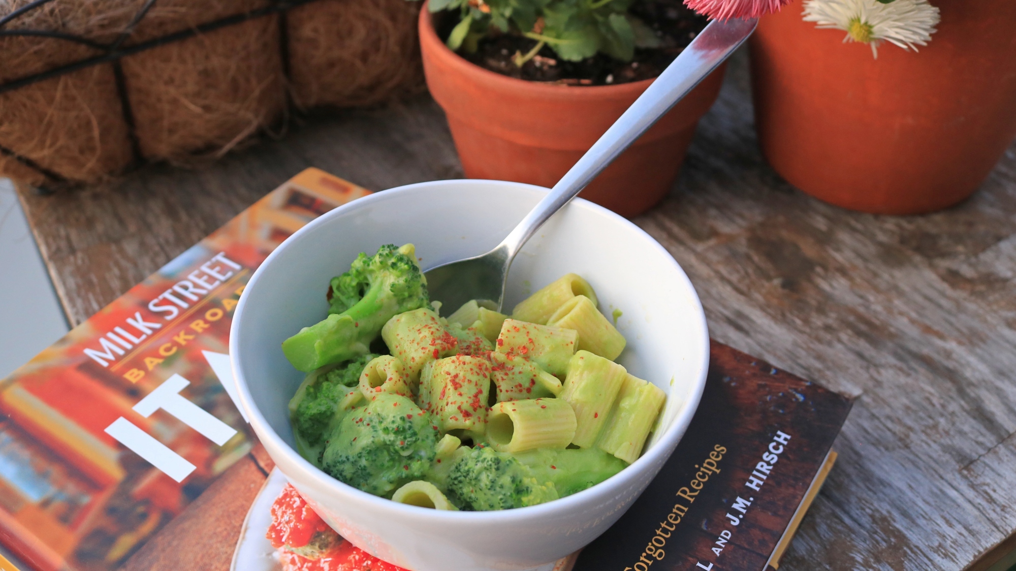 A bowl of broccoli pasta on a wooden table.