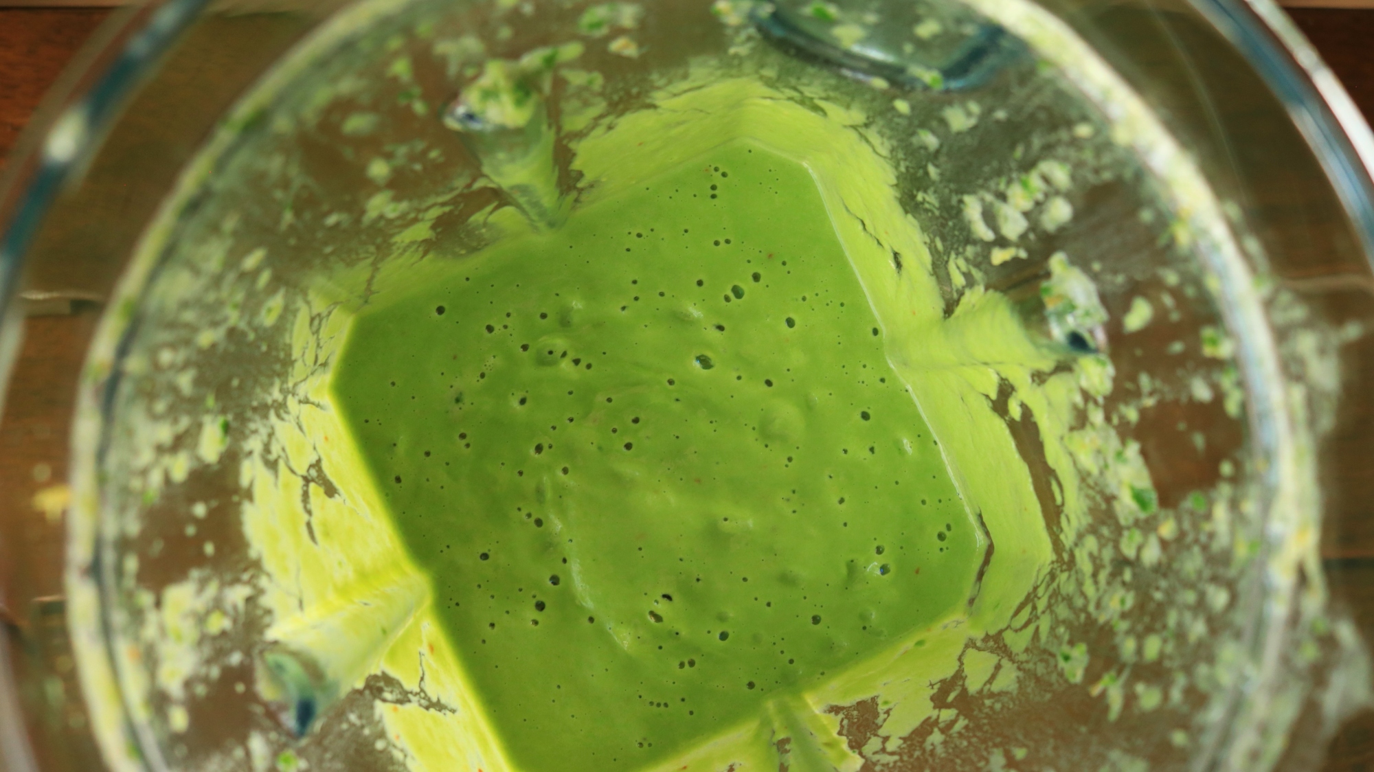 The inside of a blender container with green broccoli sauce.