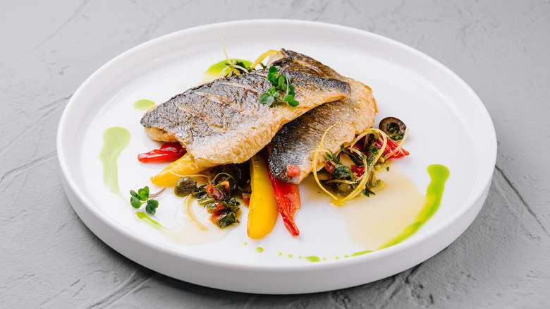 Crispy-skinned seared fish elegantly plated on seared peppers.