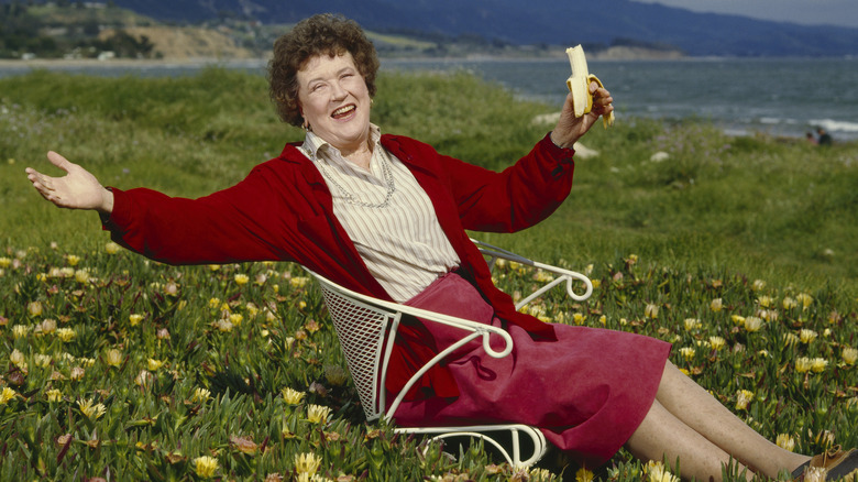 smiling Julia Child outside in chair with banana
