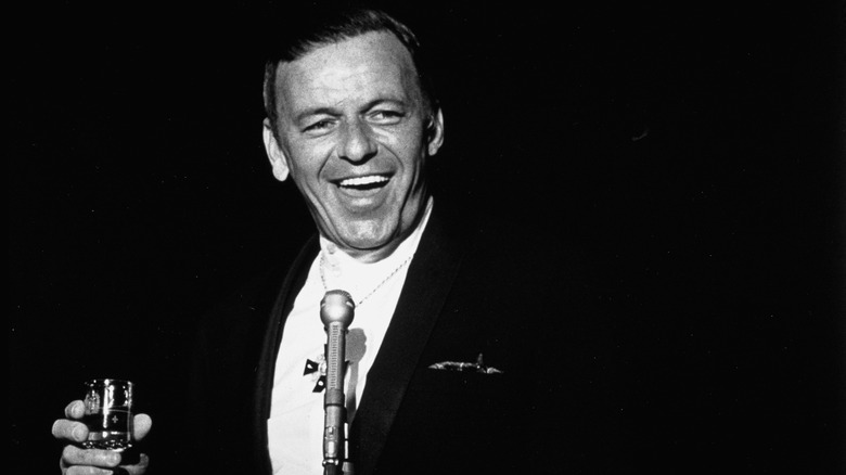 Frank Sinatra smiling and holding a glass of liquor