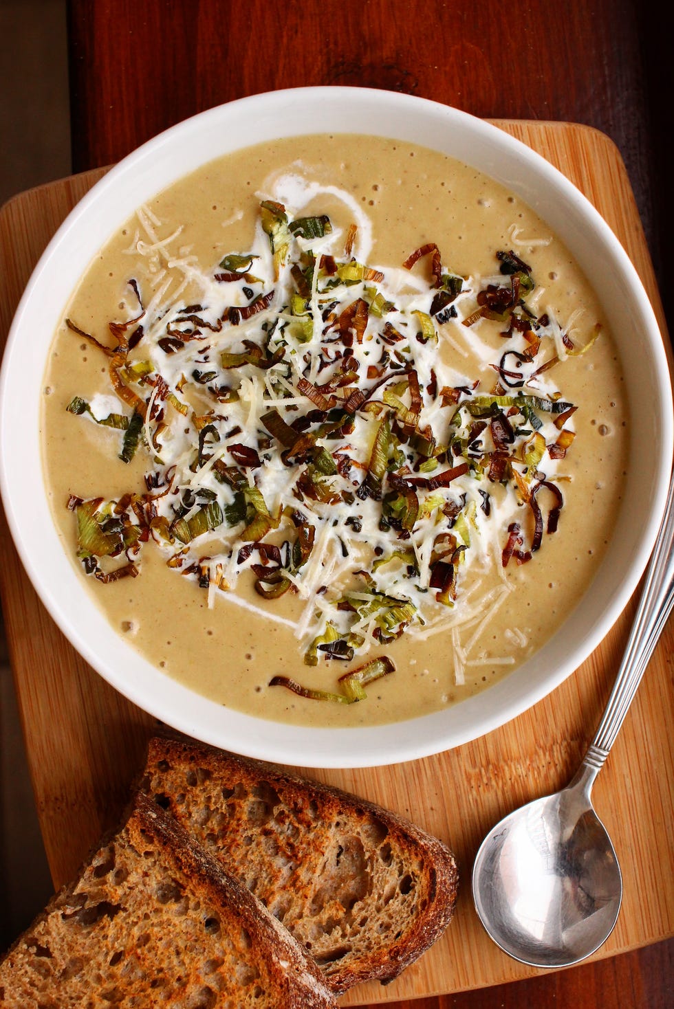 leek and potato soup in a white bowl on a dark wooden surface