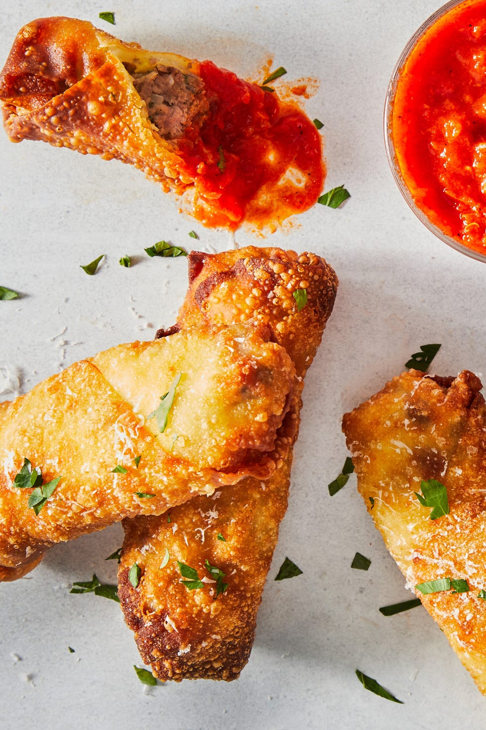 meatball sub egg rolls topped with chopped parsley and marinara