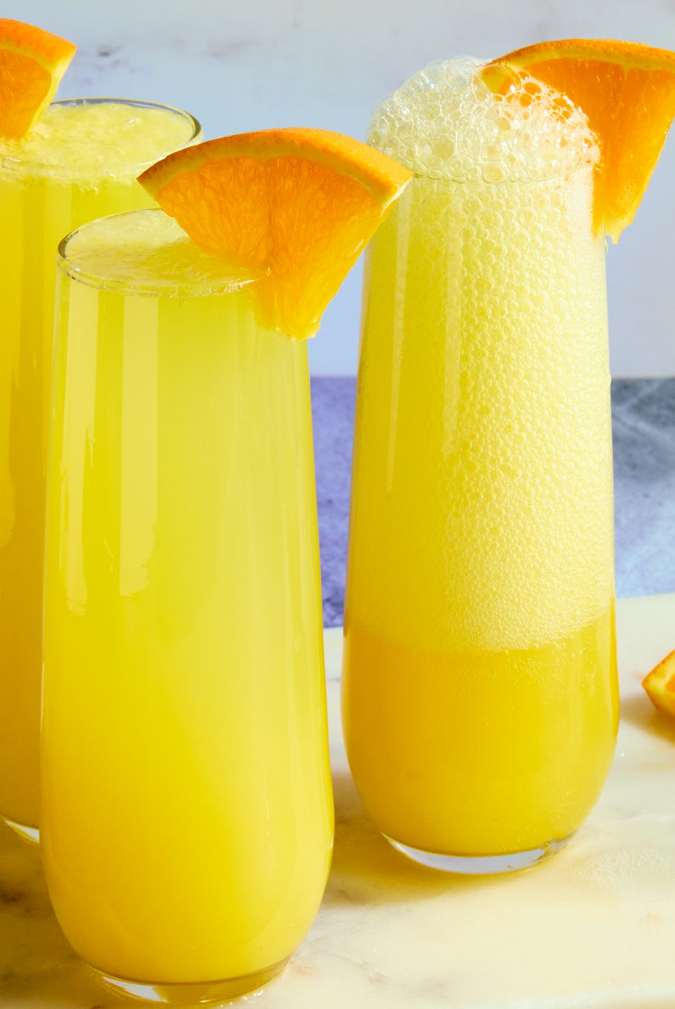 orange juice and champagne in a flute garnished with an orange wedge