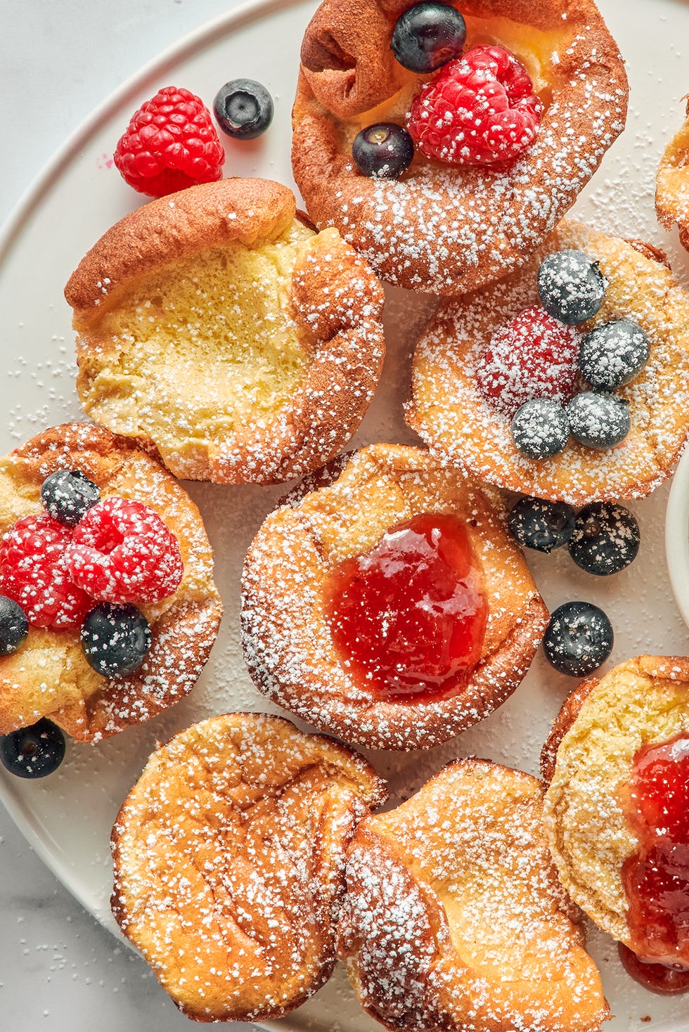 mini dutch baby pancakes with berries jam and confectioners sugar