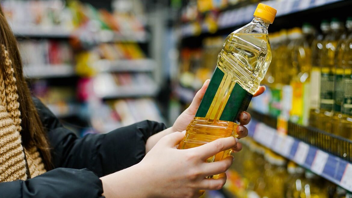 A person holds up a bottle of oil in a shop