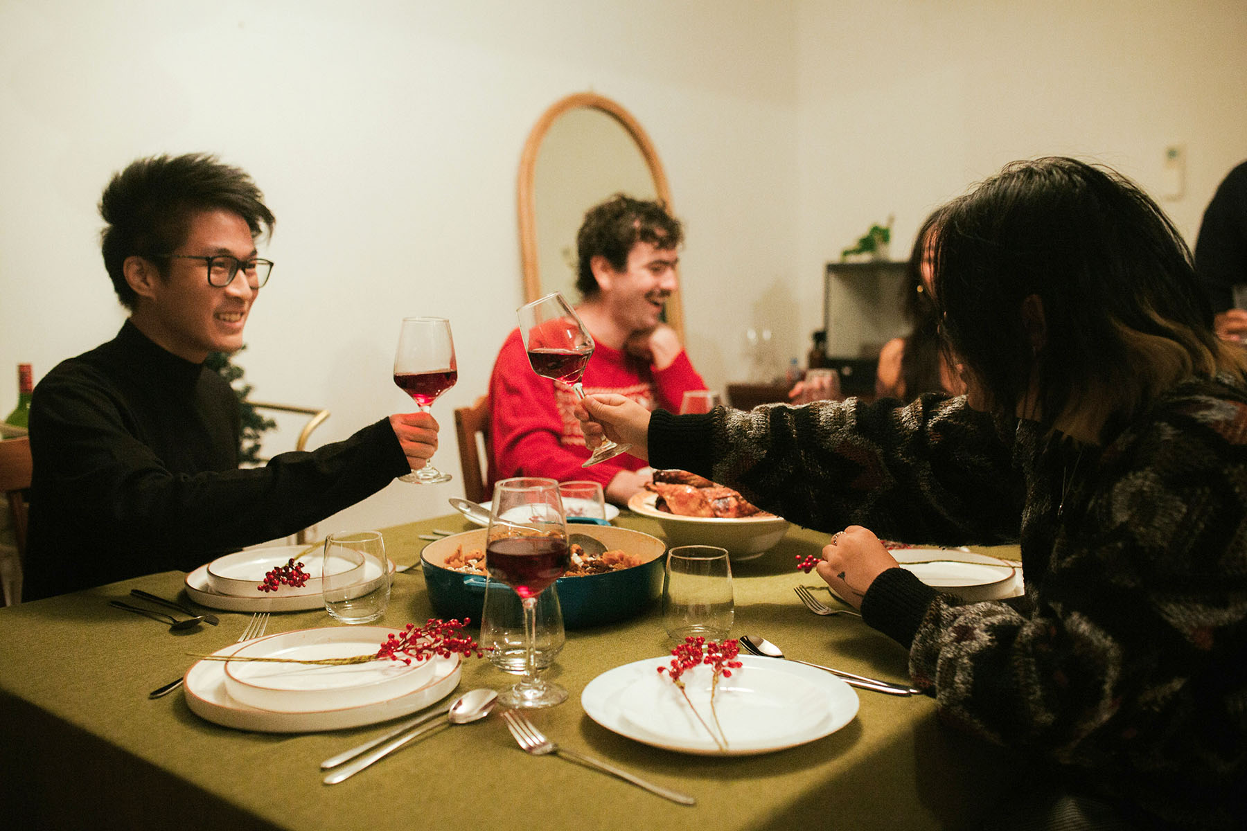 Friends toasting red wine glasses during New Year dinner.