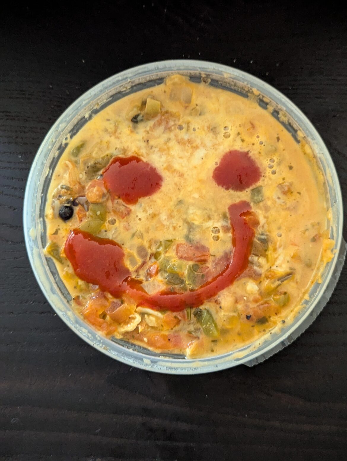 chicken burrito bowl from costco with a smiley sriracha squirt