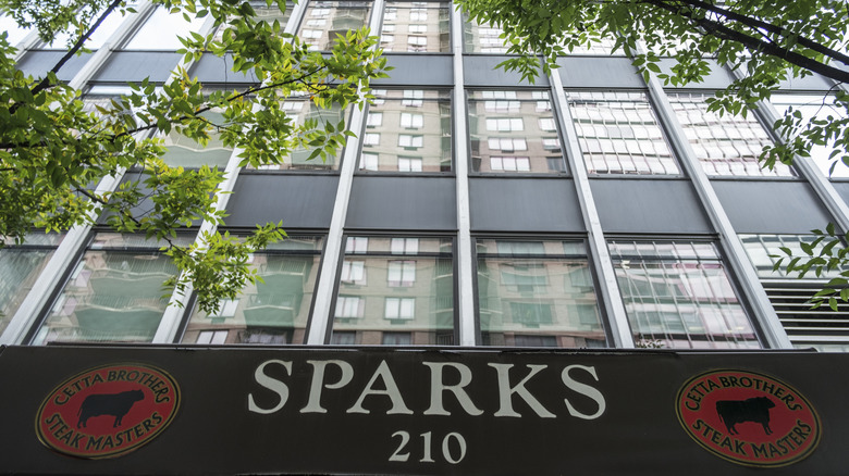 The Sparks Steakhouse signage with buildings and a tree branch above