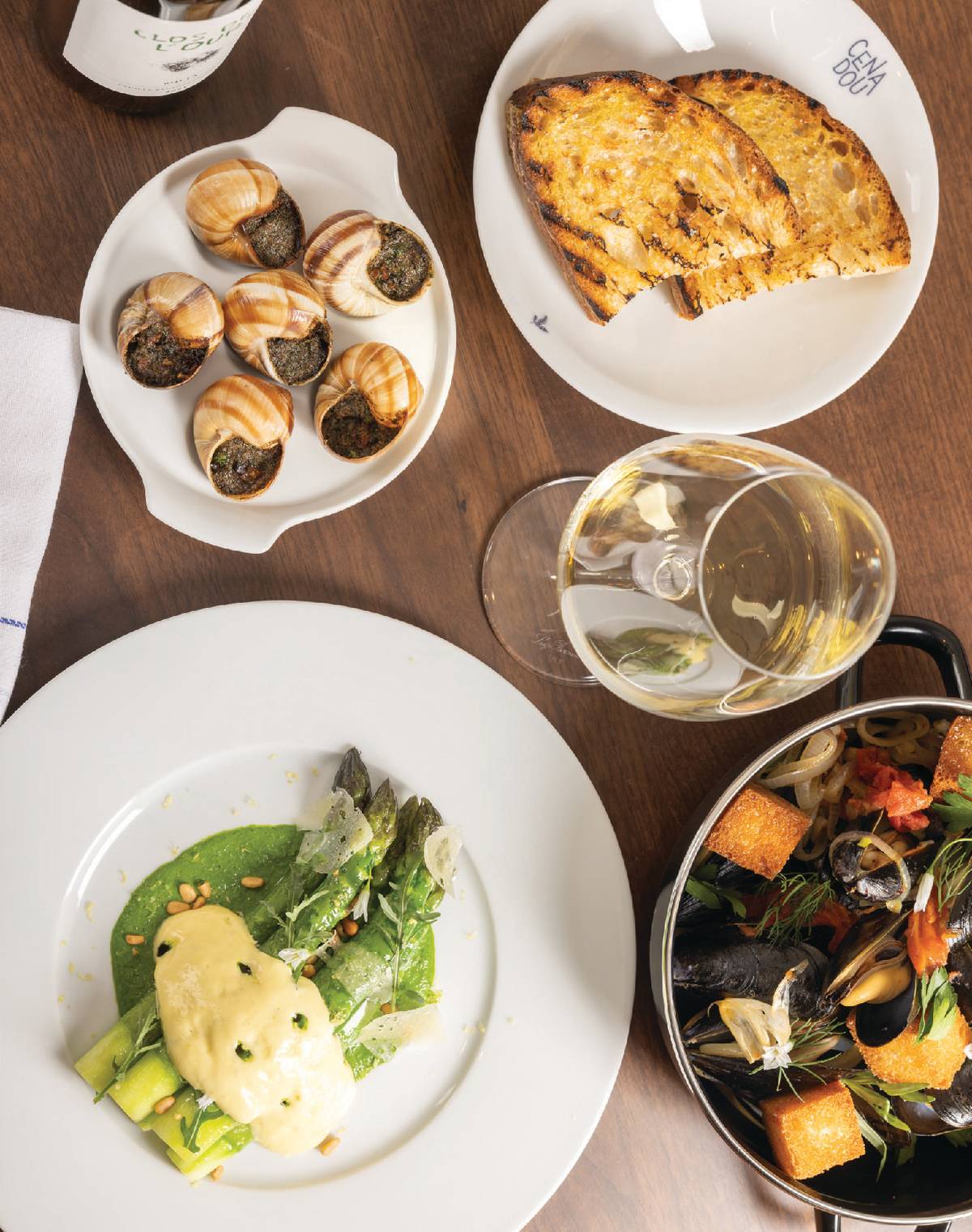 Clockwise: A trio of appetizers including escargot in puff pastry, moules à la Provençales, and poached asparagus with warm aioli emulsion and soft-boiled quail eggs