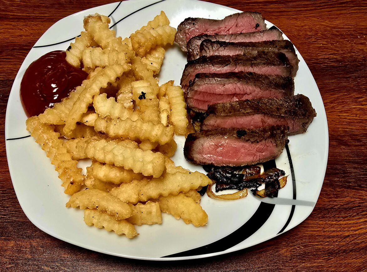 Prime Strip Steak over a bed of grilled onions in a pepper jelly and fries.