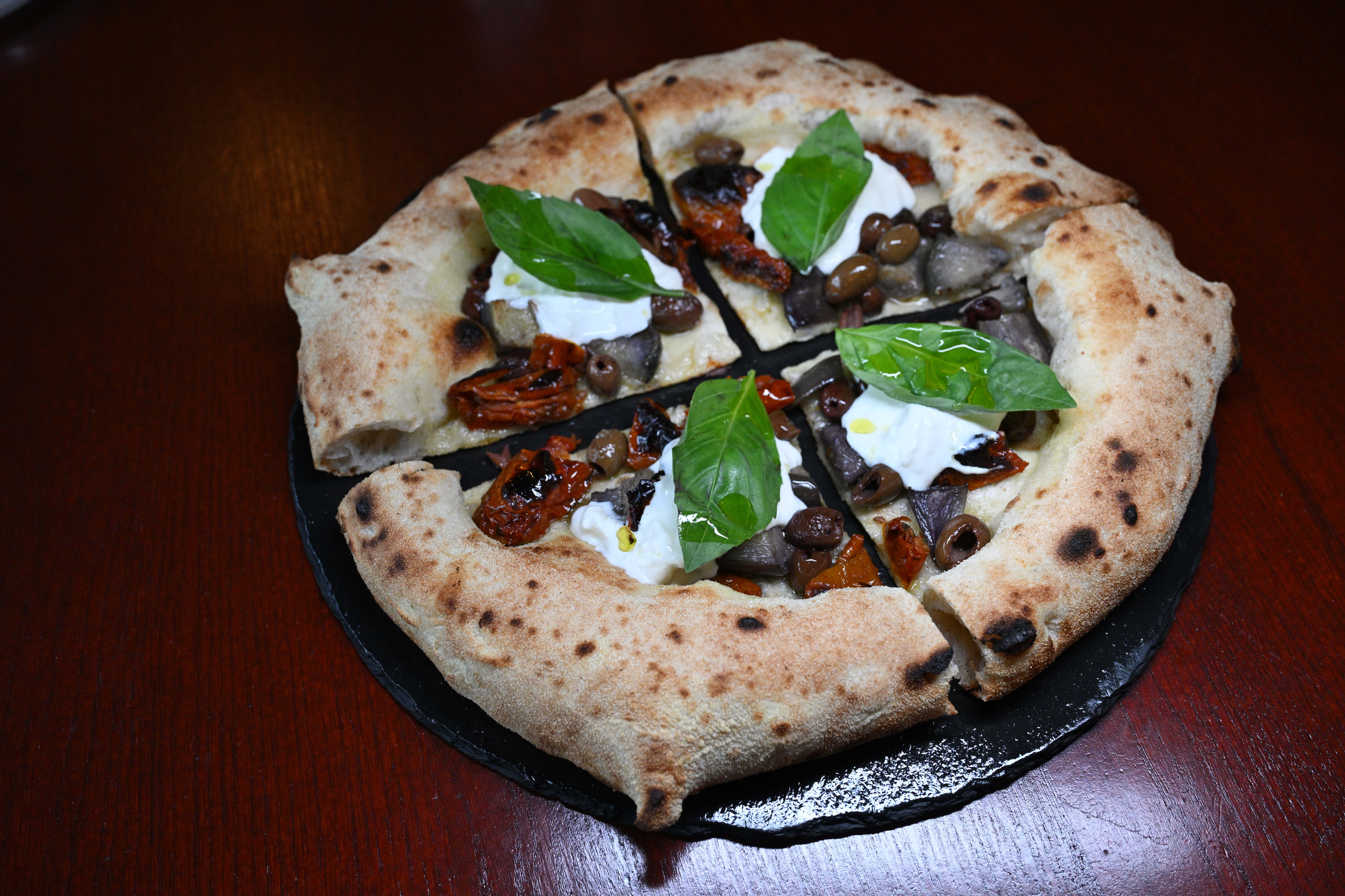 Pizza with sun-dried tomatoes, olives, and burrata.