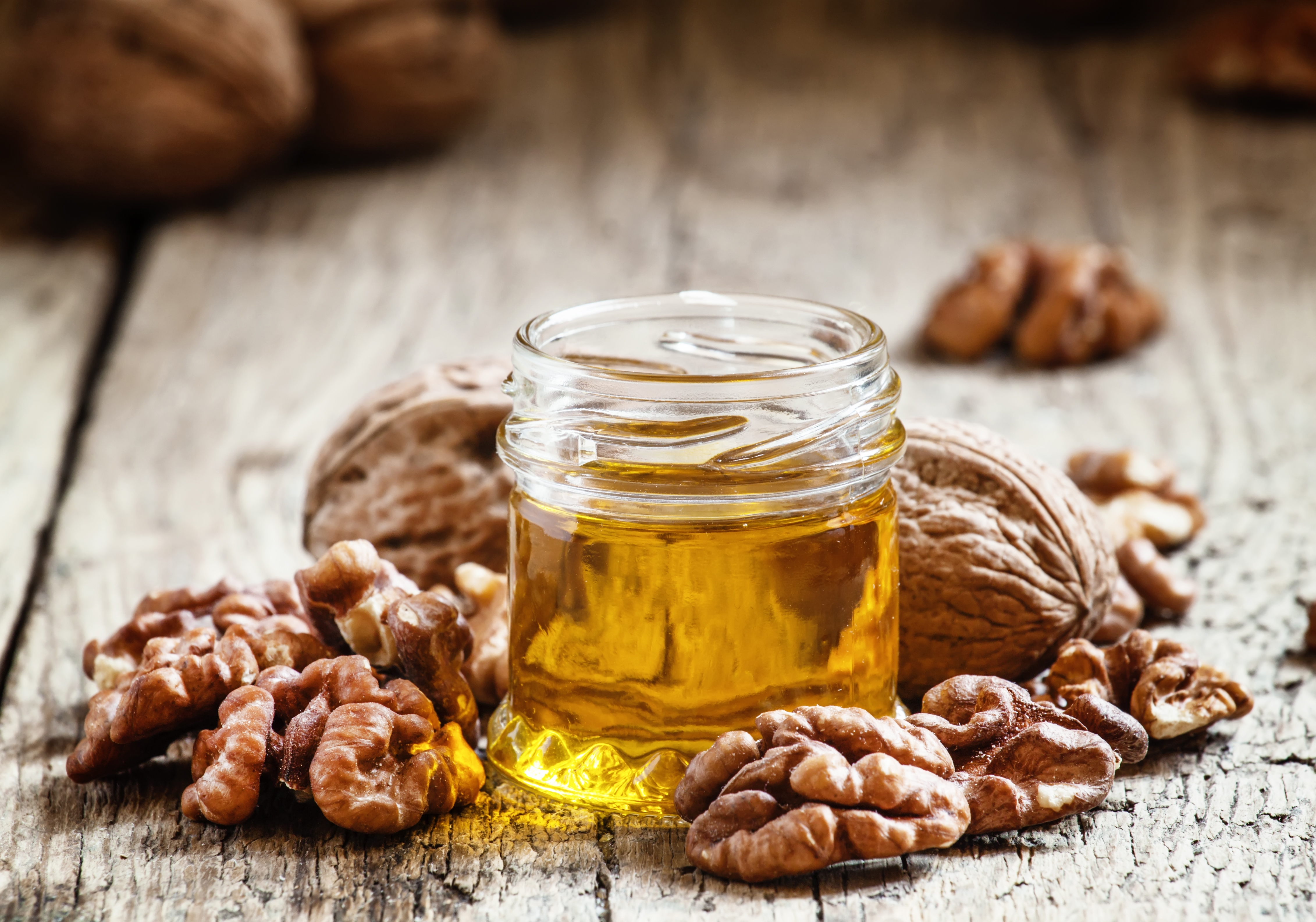 Walnut oil in a small jar with walnut kernels.