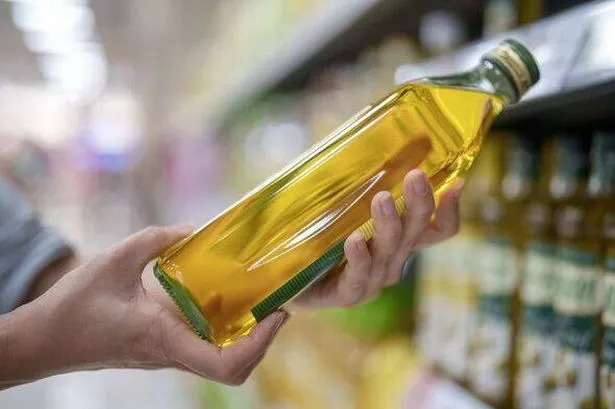 Shopper picking up olive oil from supermarket shelf