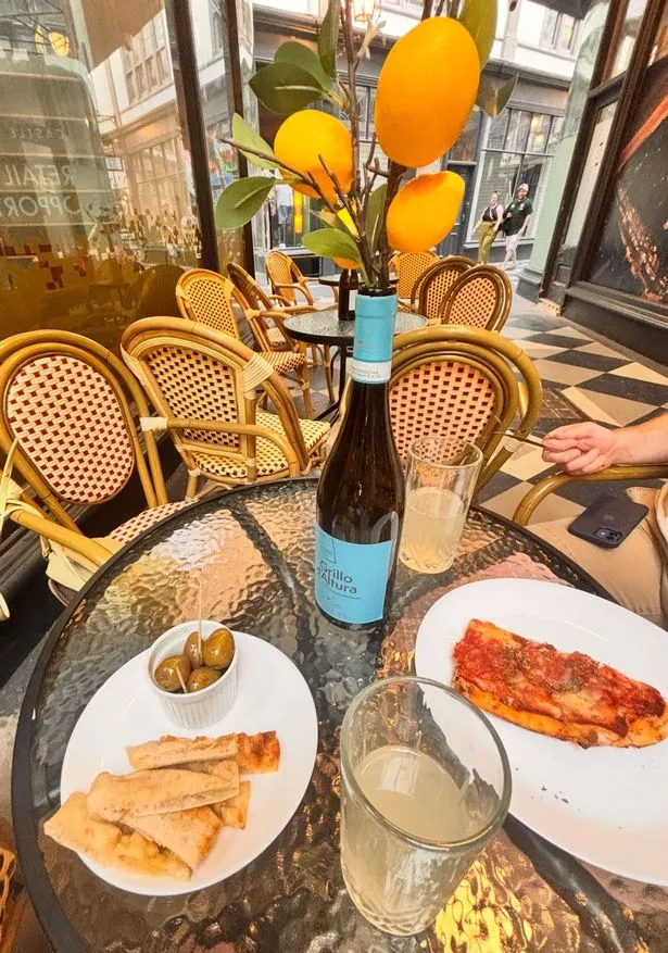 Olives, bread, lemonade and a pizza slice from Khione