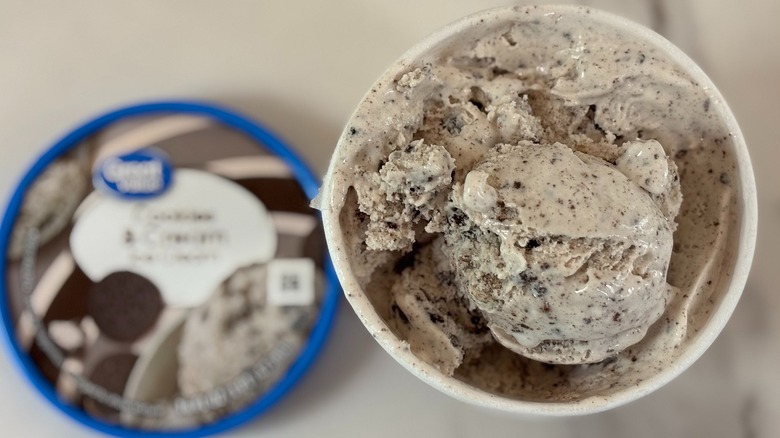 Top-down view of open tub of Great Value Cookies & Cream ice cream next to lid on white table