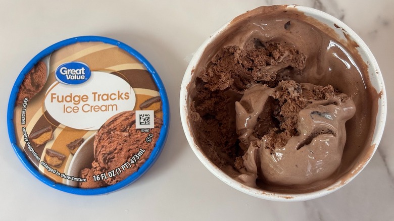 Top-down view of open tub of Great Value Fudge Tracks ice cream next to lid on white table