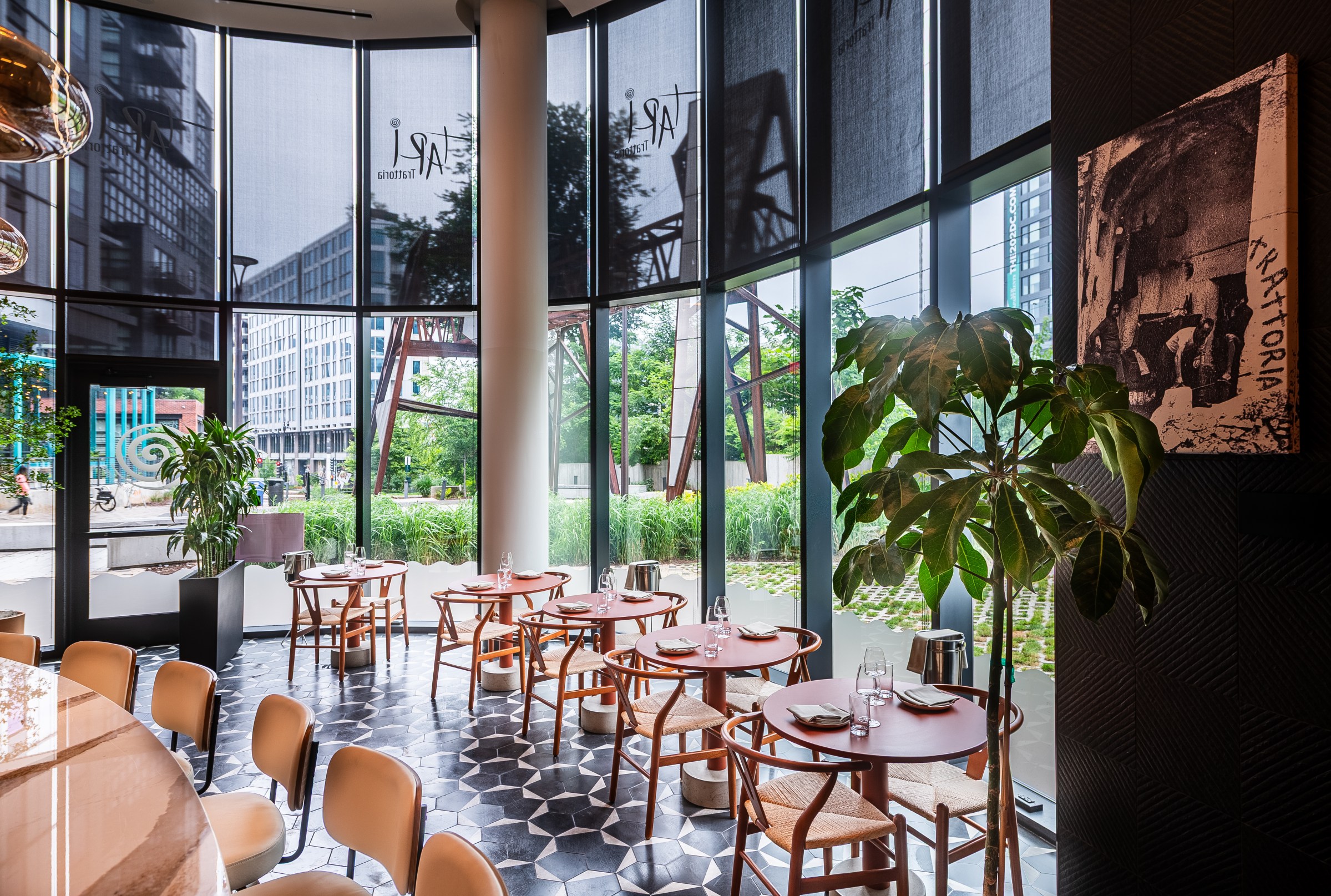 light-washed wood tables, a black and white tiled floor surrounded by windows.