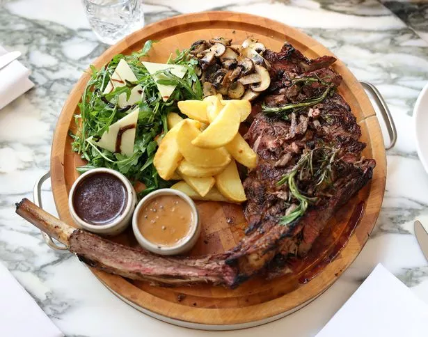 The Tomahawk (42oz) of prime beef rib, served with sautéed mushrooms, wild rocket and parmesan salad, hand cut chips and a selection of sauces