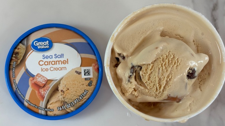Top-down view of open tub of Great Value Sea Salt Caramel ice cream next to lid on white table