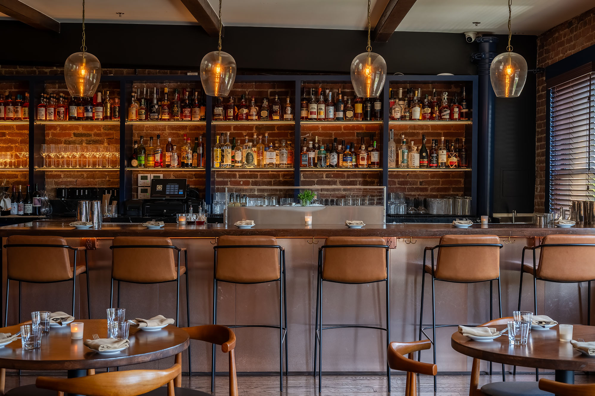 A modern bar with brick walls and high chairs. 