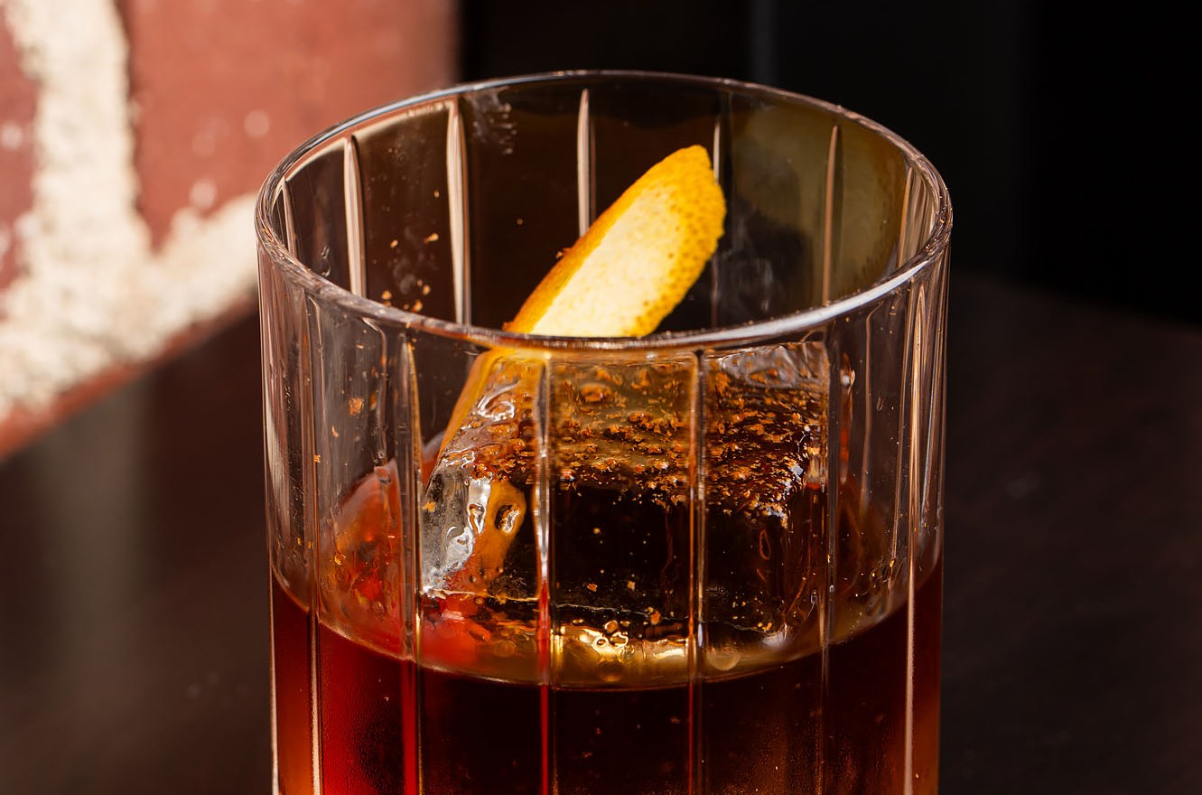 A simple whiskey cocktail with orange garnish.