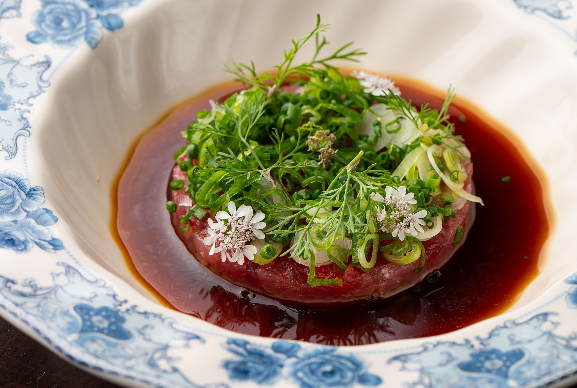 Chopped fish in a circle topped with edible greens.
