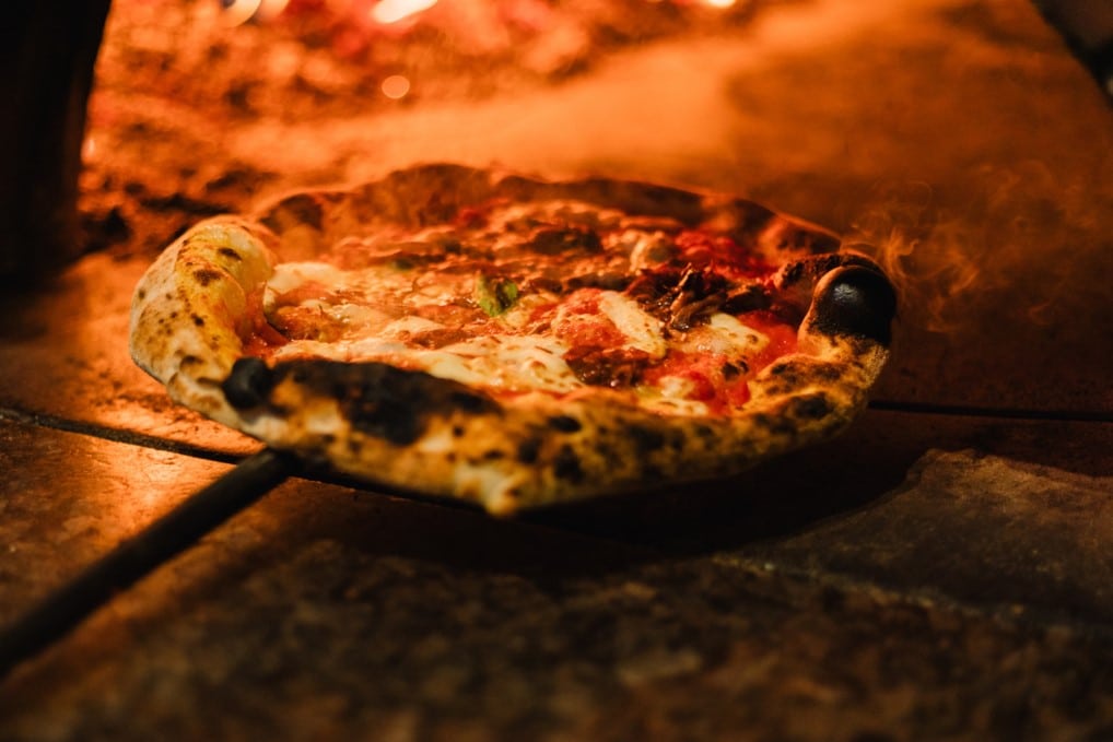 Pizza cooking in wood-fired oven at Alicia's