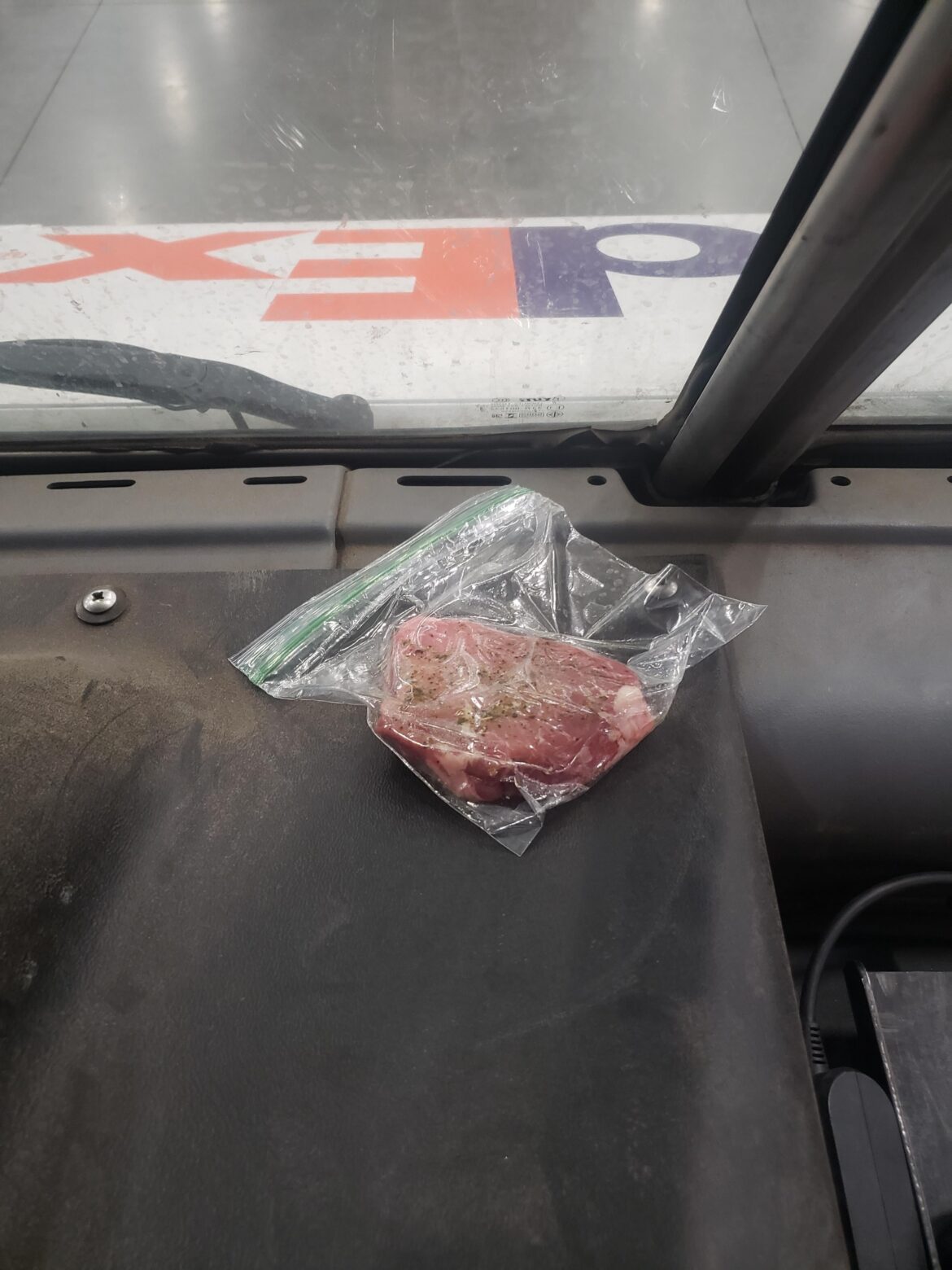 Dude cooks a steak on his dash.