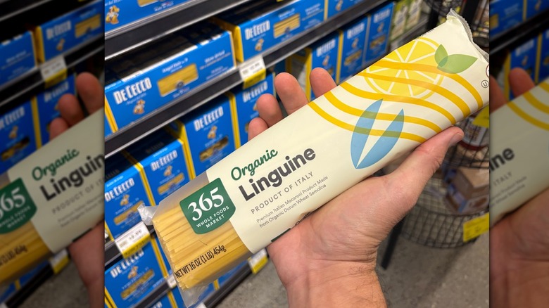 Hand holding a yellow package of linguini