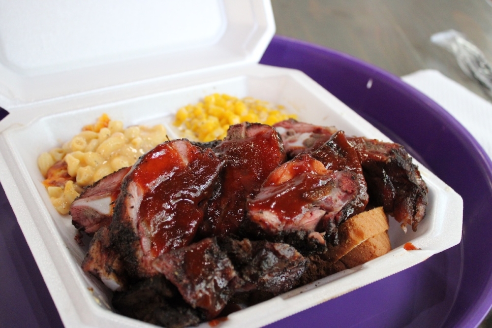 The Purple Pig serves up BBQ, midwestern-style A takeout box full of ribs, cream corn, and baked mac and cheese.