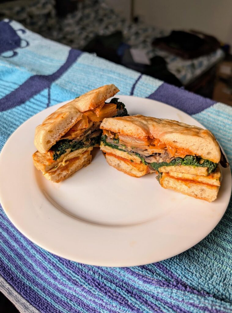 Flat bagel with tempeh, mushrooms, spinach, kimchi and a pb powder gochujang sauce