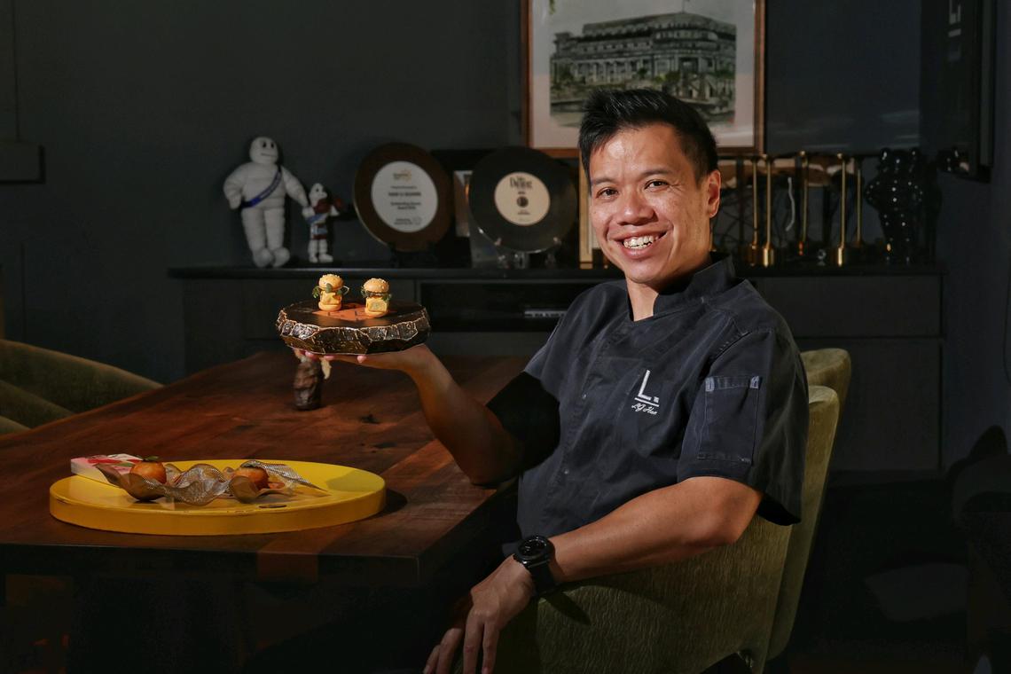 Michelin-starred chef LG Han with Ramly burger (in hand) and oyster bao presented on a mini hawker table at Labyrinth on Dec 4, 2024. Feature on Southeast Asian fine dining restaurants and their plans for 2025.
