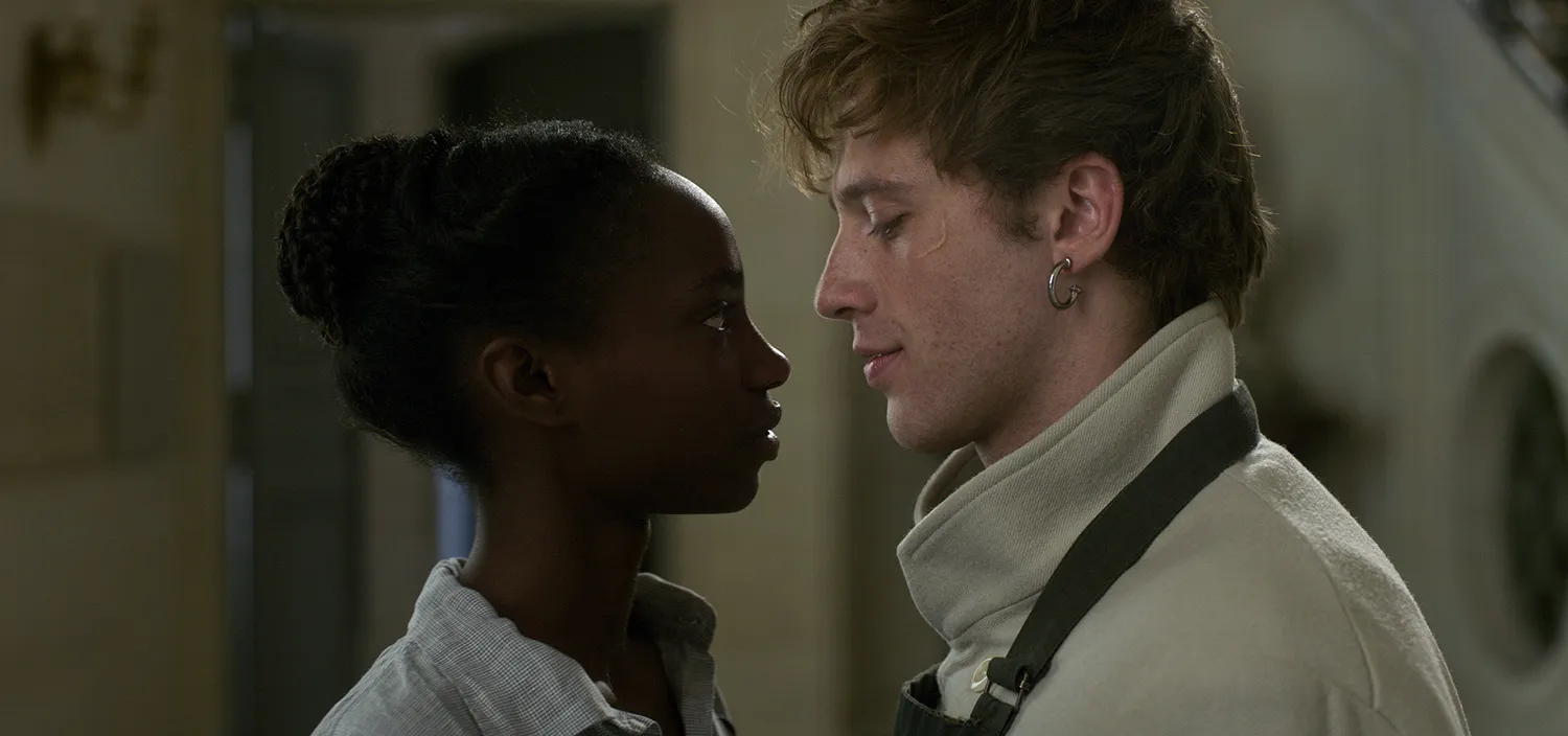 A man and a woman stand close while looking at each other.