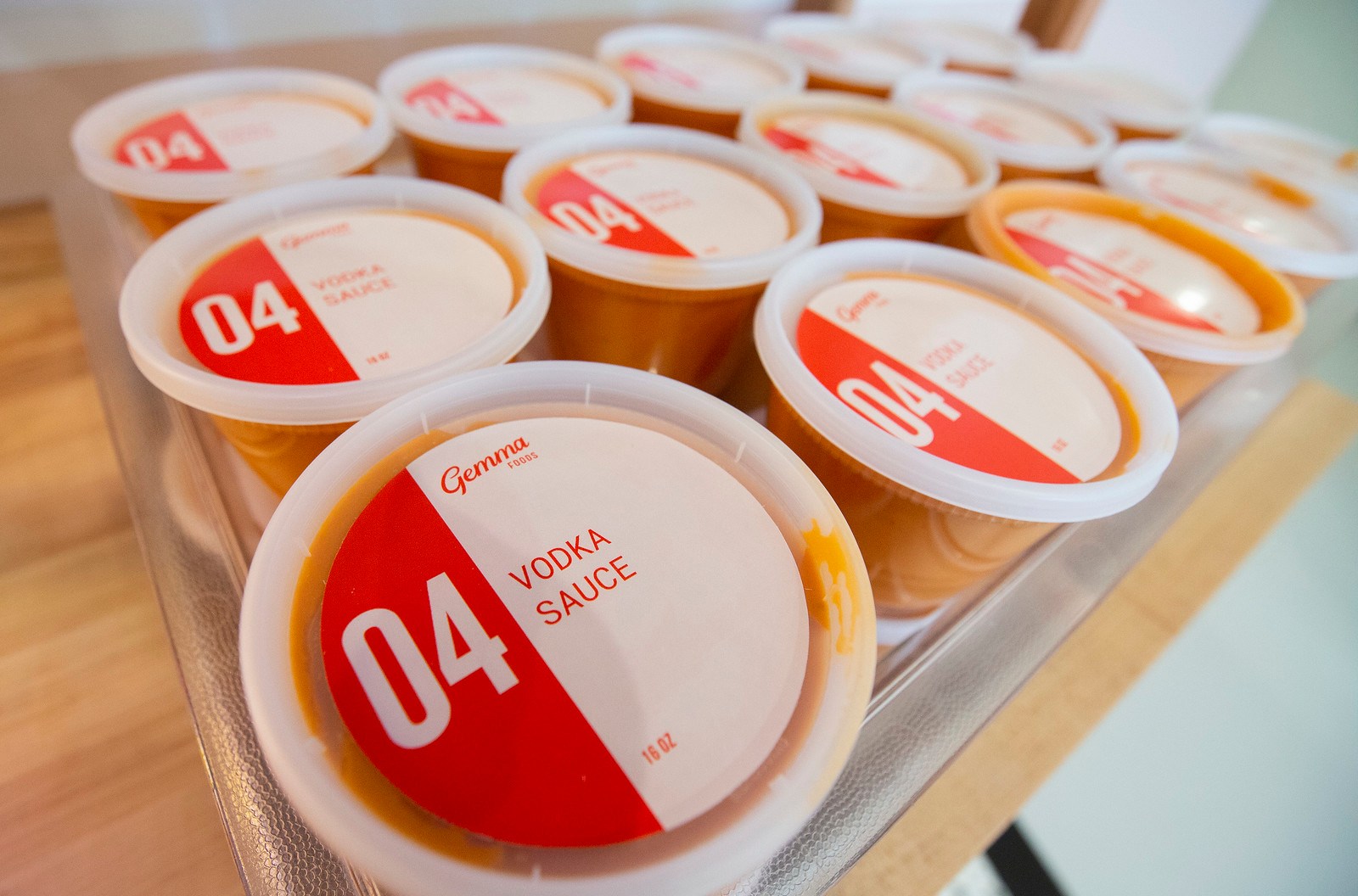 A bin of plastic containers labeled “vodka sauce” on the lid.