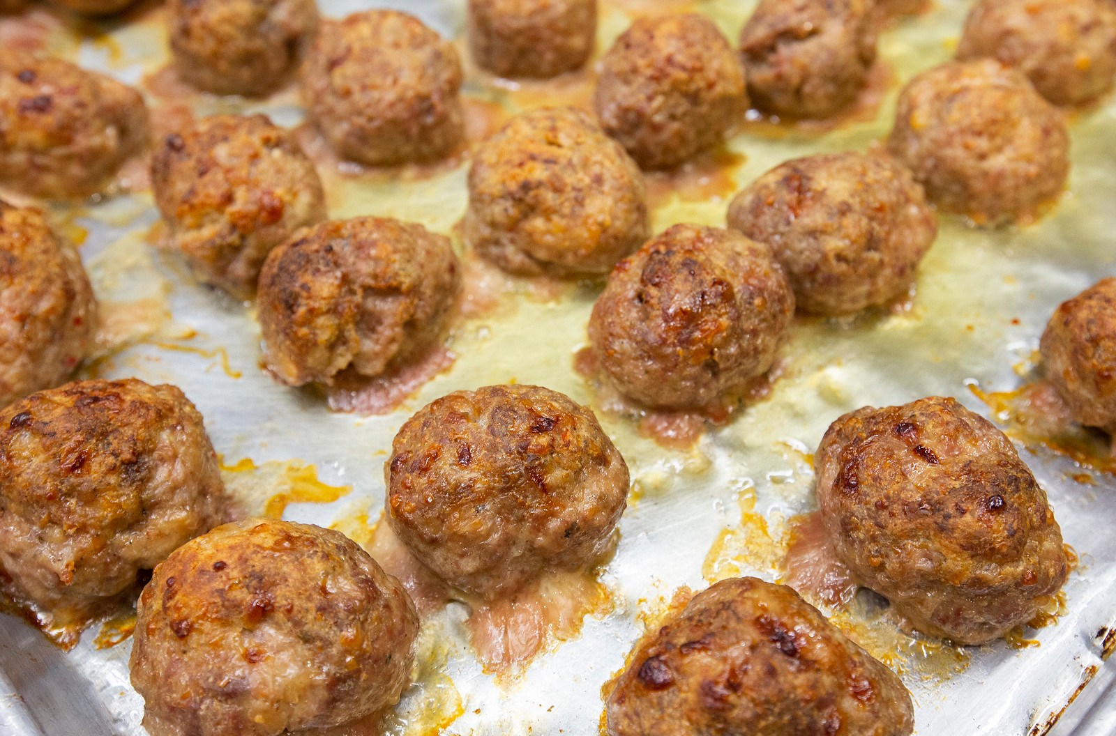 Close-up of a sheet pan of baked meatballs.