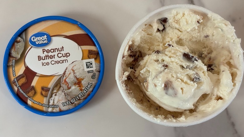 Top-down view of open tub of Great Value Peanut Butter Cup ice cream next to lid on white table