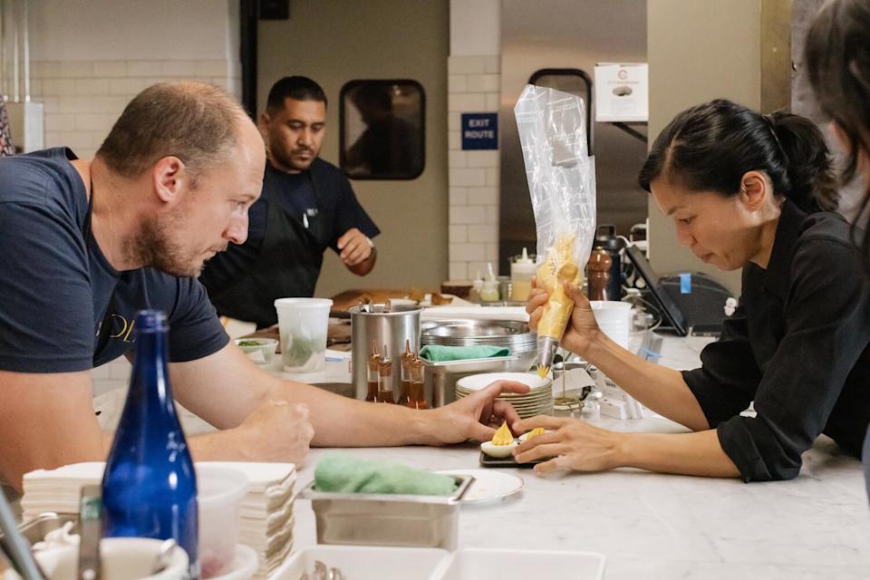 Beran and Hsing prep a plate of deviled eggs in the kitchen before friends and family service.