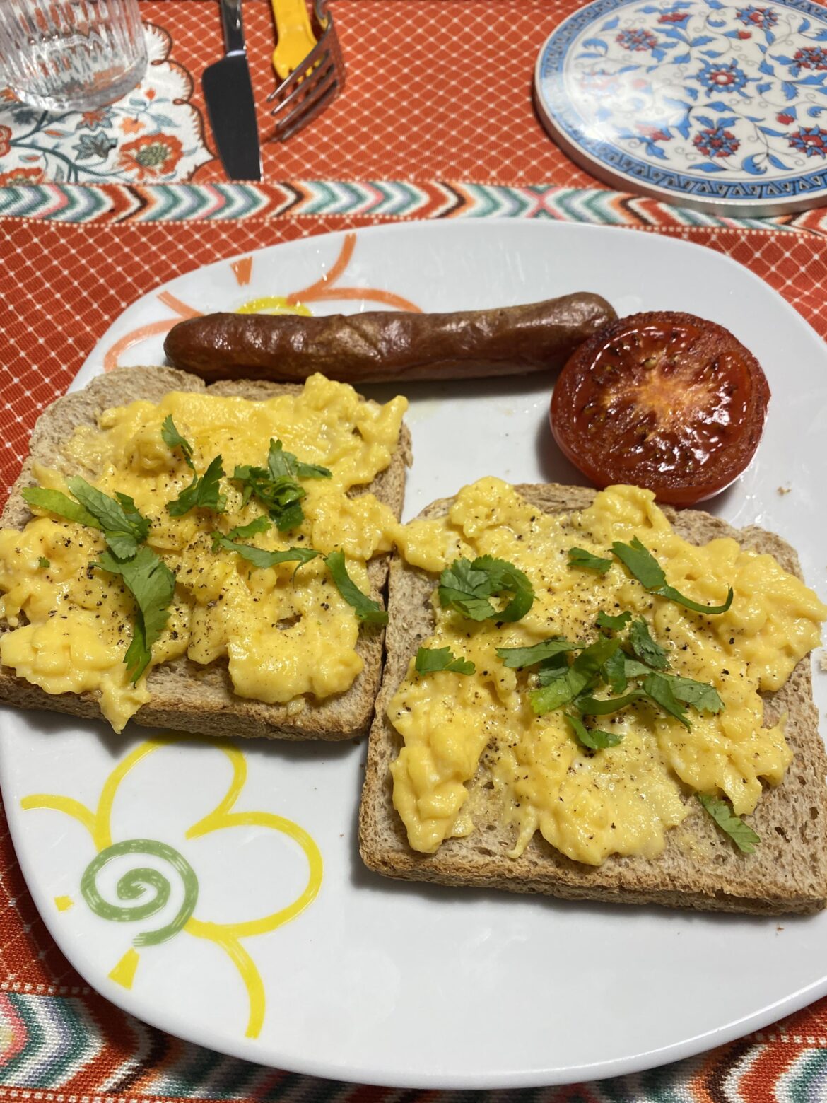 Scrambled eggs on toast with hot dog and fried tomato