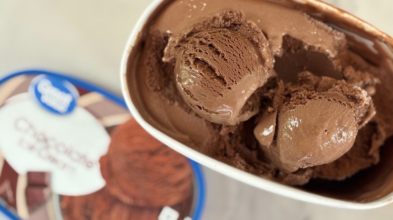 Top-down view of open tub of Great Value Chocolate ice cream next to lid on white table
