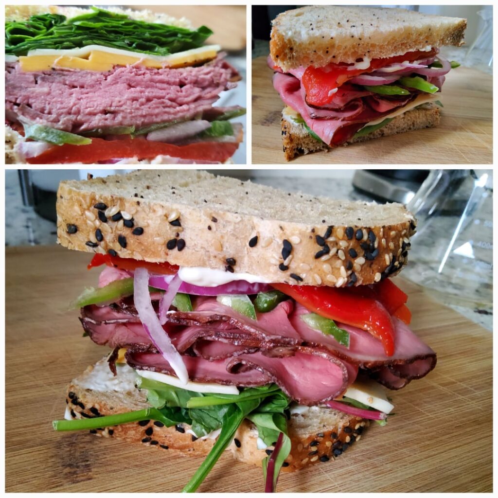 Deli beef sandwich packed with veggies on sourdough everything bread