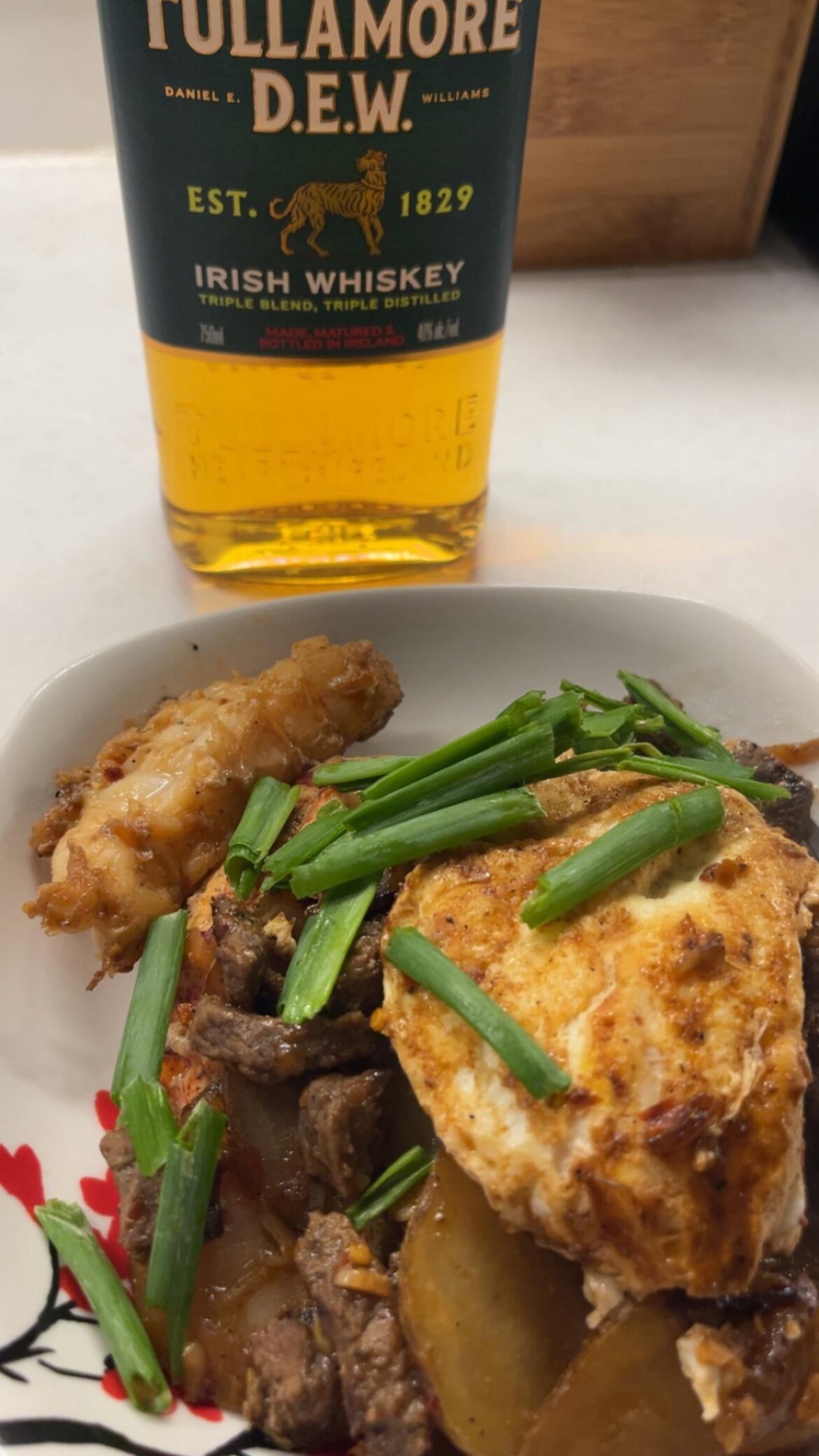 A surf and turf breakfast with beef, lobster tail, potatoes and an egg