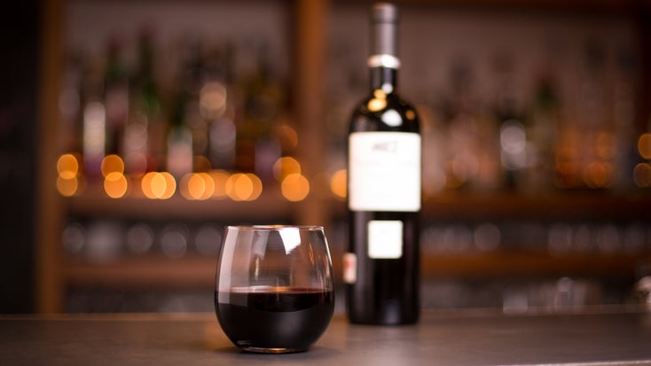 A moody close-up of a glass of red wine at a bar.