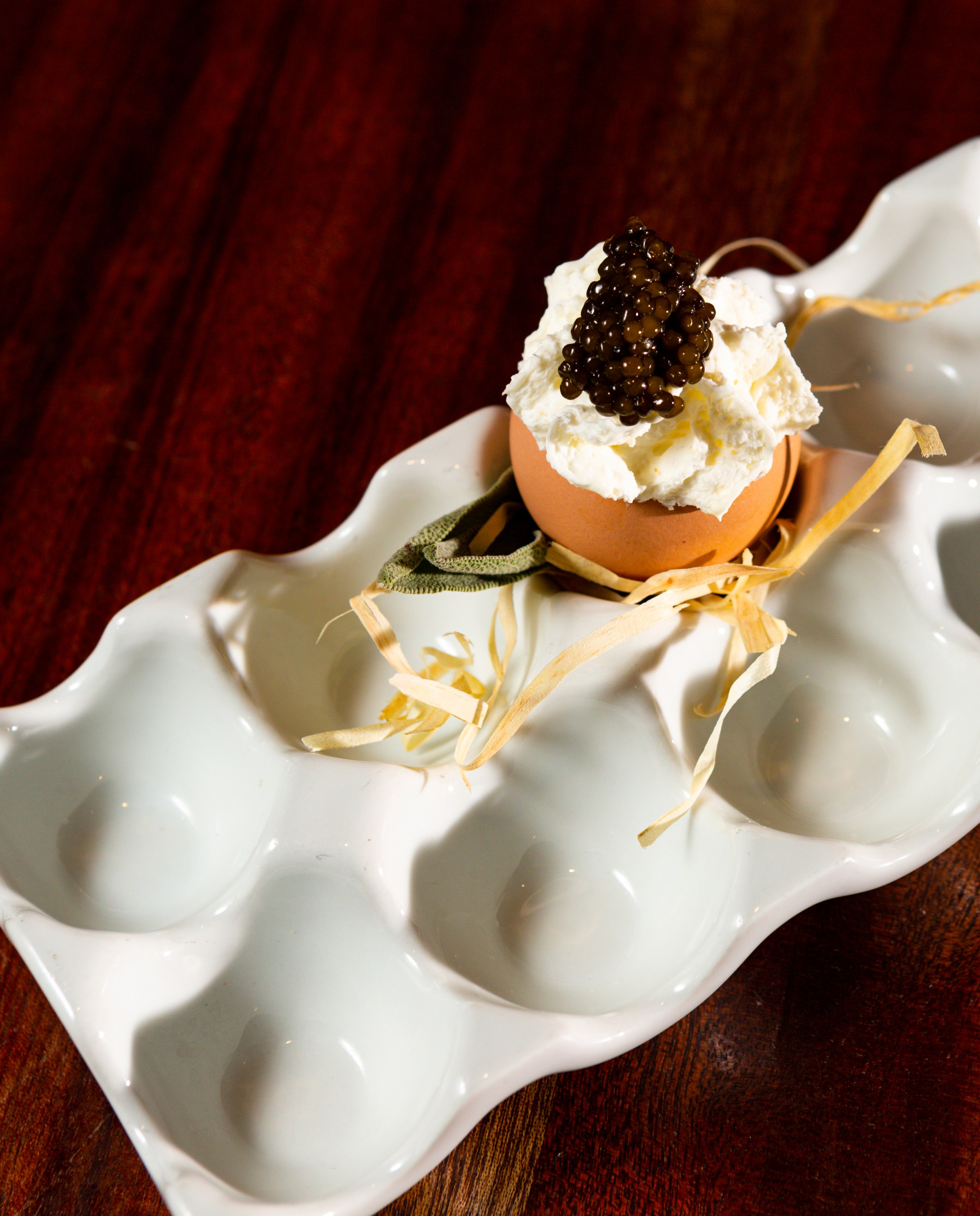 A parfait of egg yolk and caviar in an eggshell.