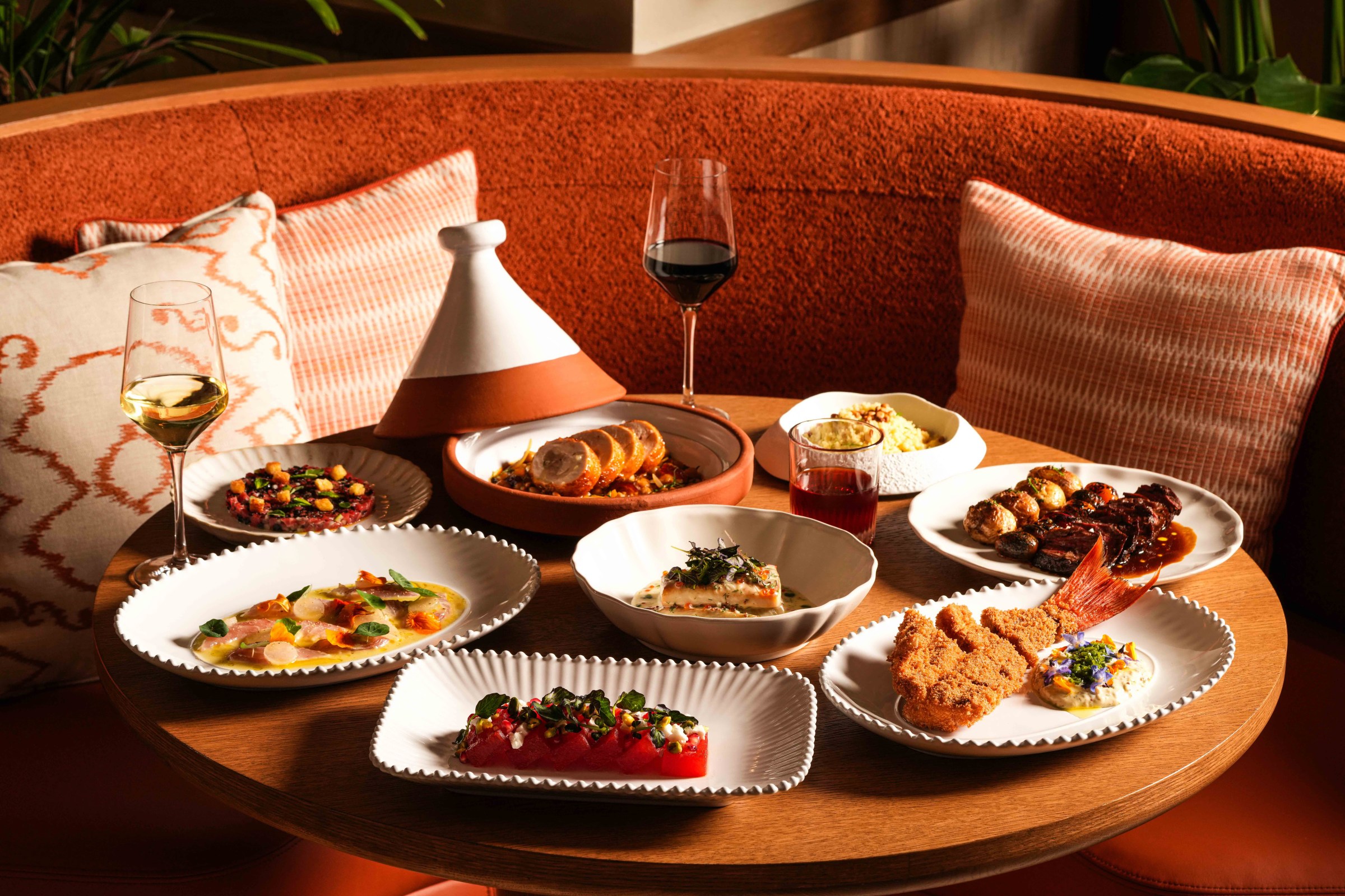 A table full of dips, small bites, and a glass of wine.